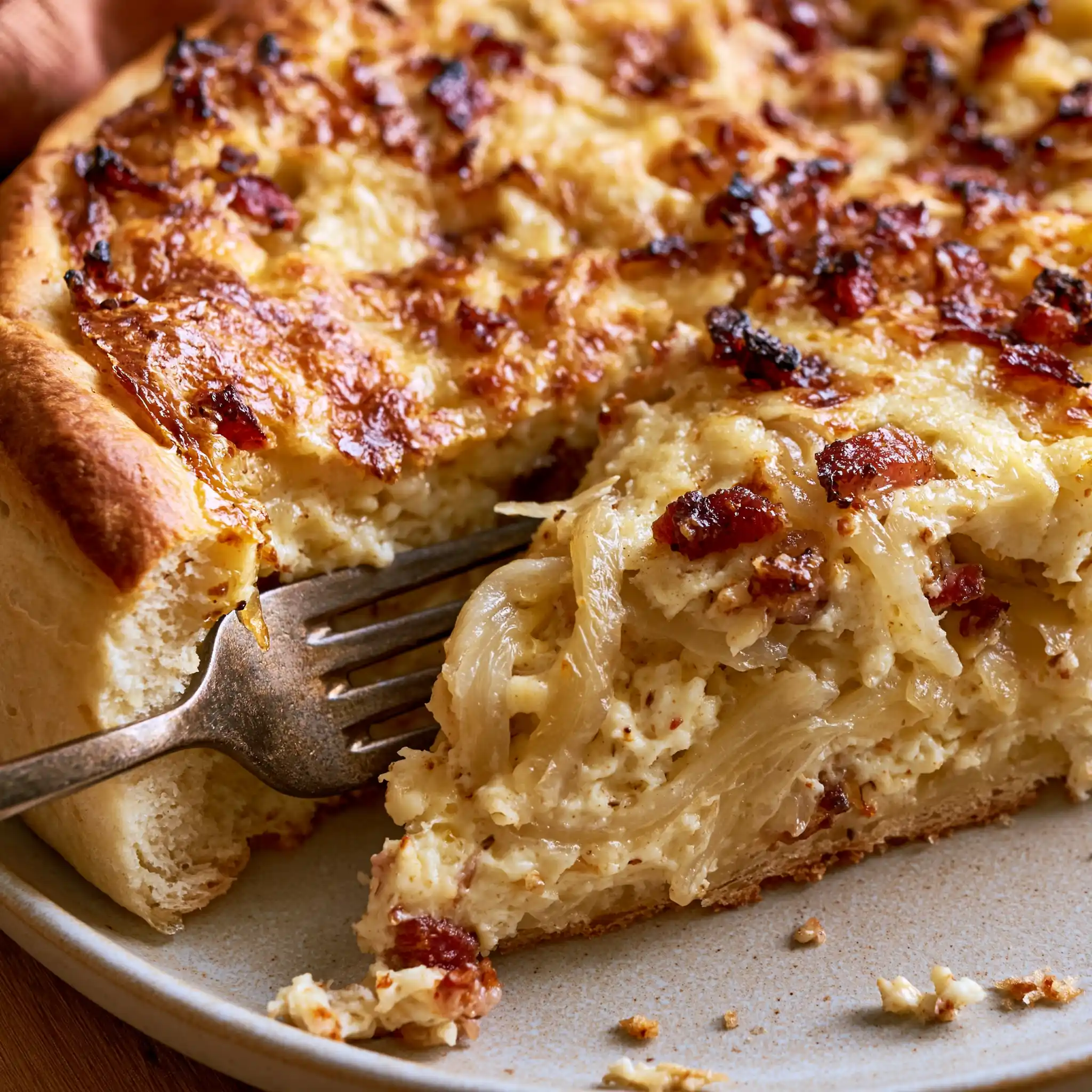 Nahaufnahme von schwäbischem Zwiebelkuchen mit cremiger Zwiebel-Speck-Füllung und lockerem Hefeteig