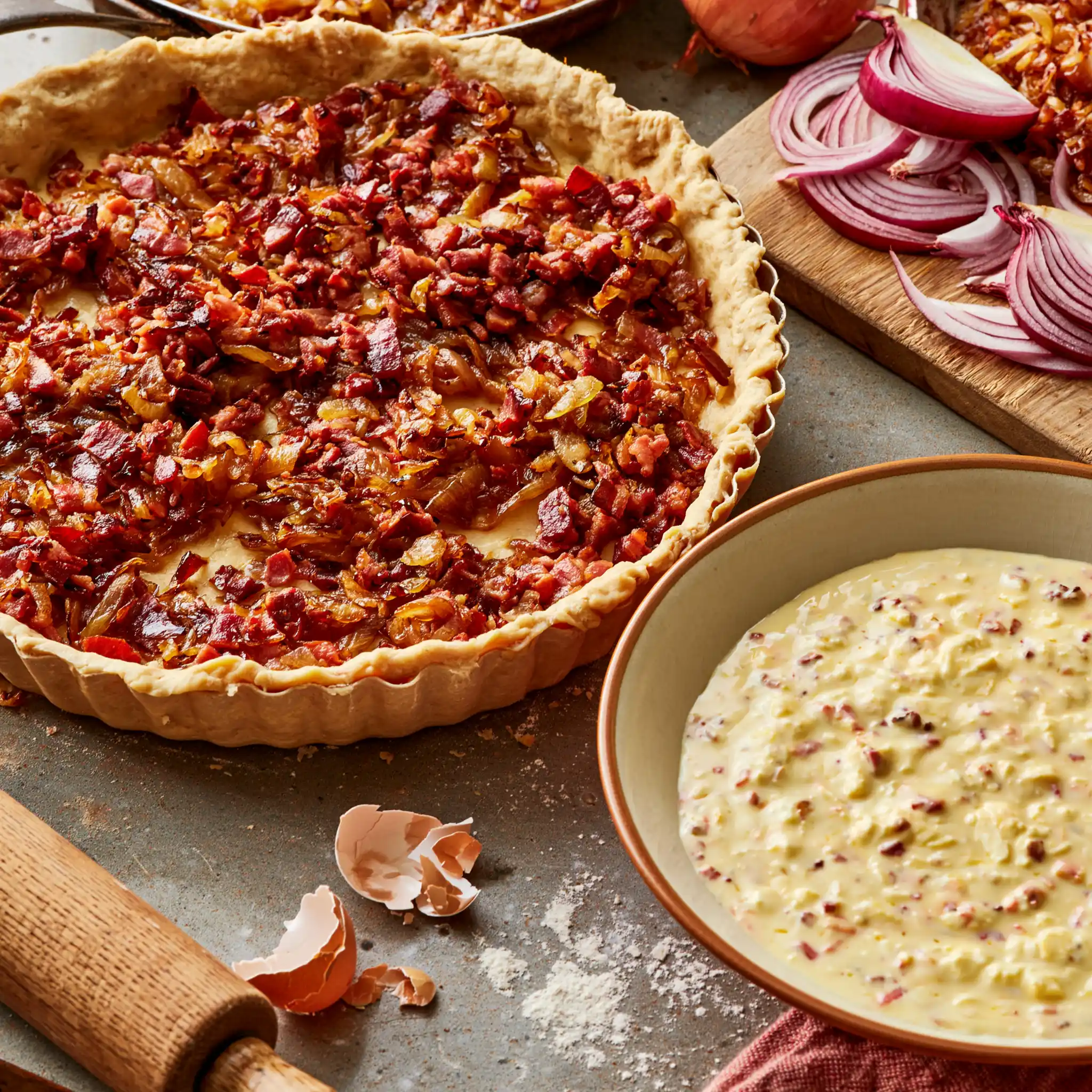 Zwiebeln und Speck werden für schwäbischen Zwiebelkuchen langsam in der Pfanne gedünstet